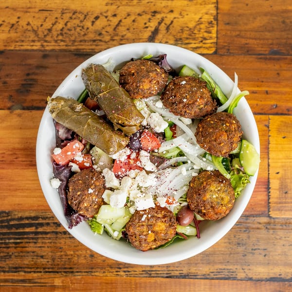 Mediterranean salad with falafel, stuffed grape leaves, feta, tomatoes, cucumbers, and onions.